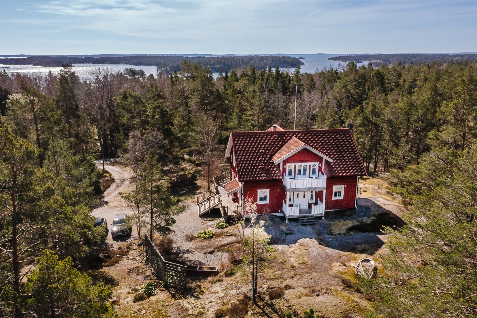 Maison suédoise rouge entourée de pins, vue aérienne sur l’archipel à Ingarö